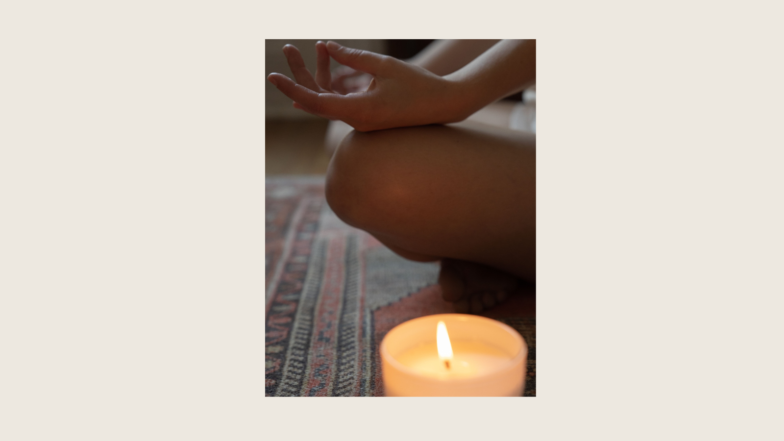 Person sitzt im Schneidersitz auf einem Teppich und praktiziert eine ruhige Meditation bei Kerzenlicht.